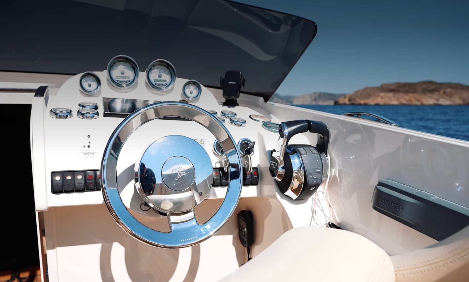 The helm of a boat at sea fitted with the SeaRebbel autopilot, its controls beside the wheel